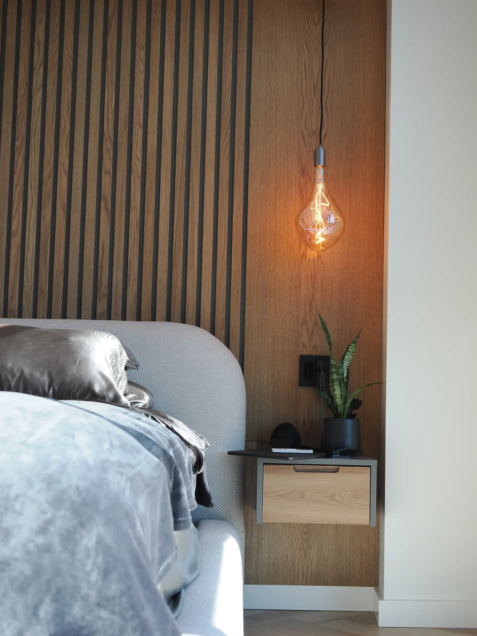 Floating bedside drawer alongside the wood wall