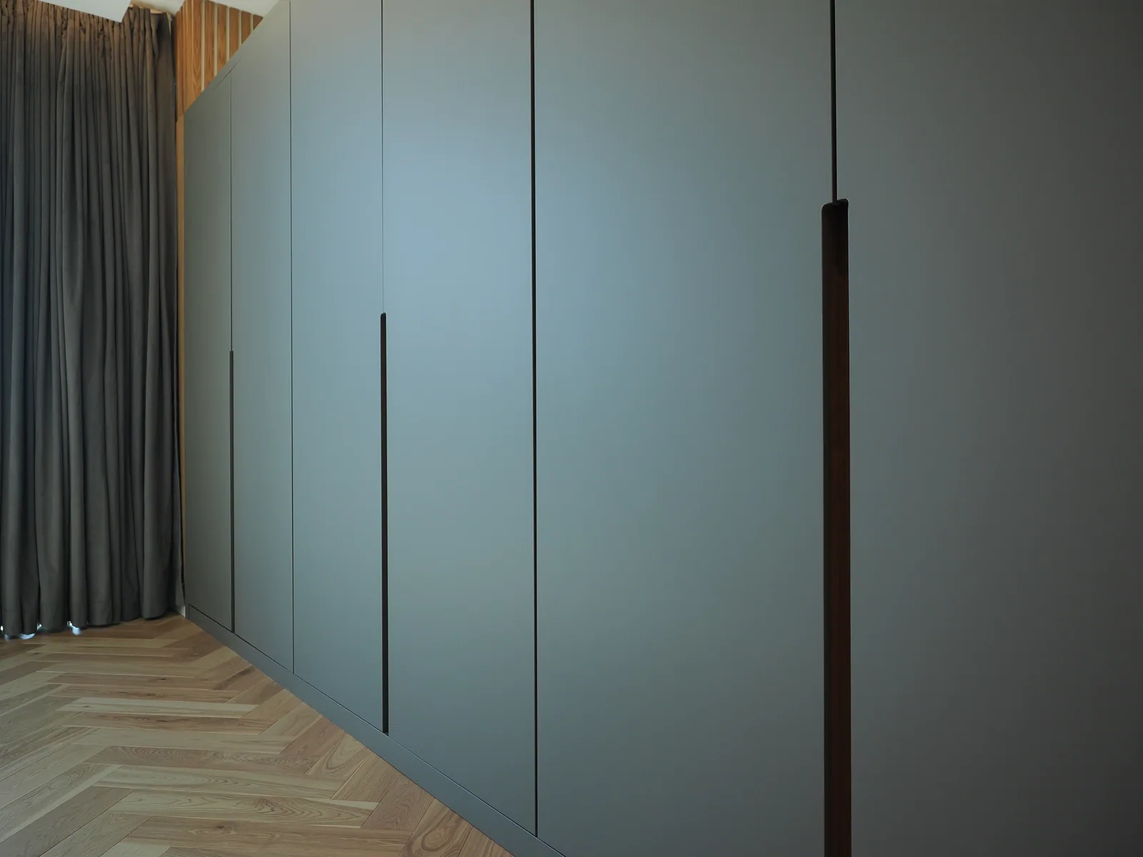 Full-height slate-blue wardrobe and long wood handles