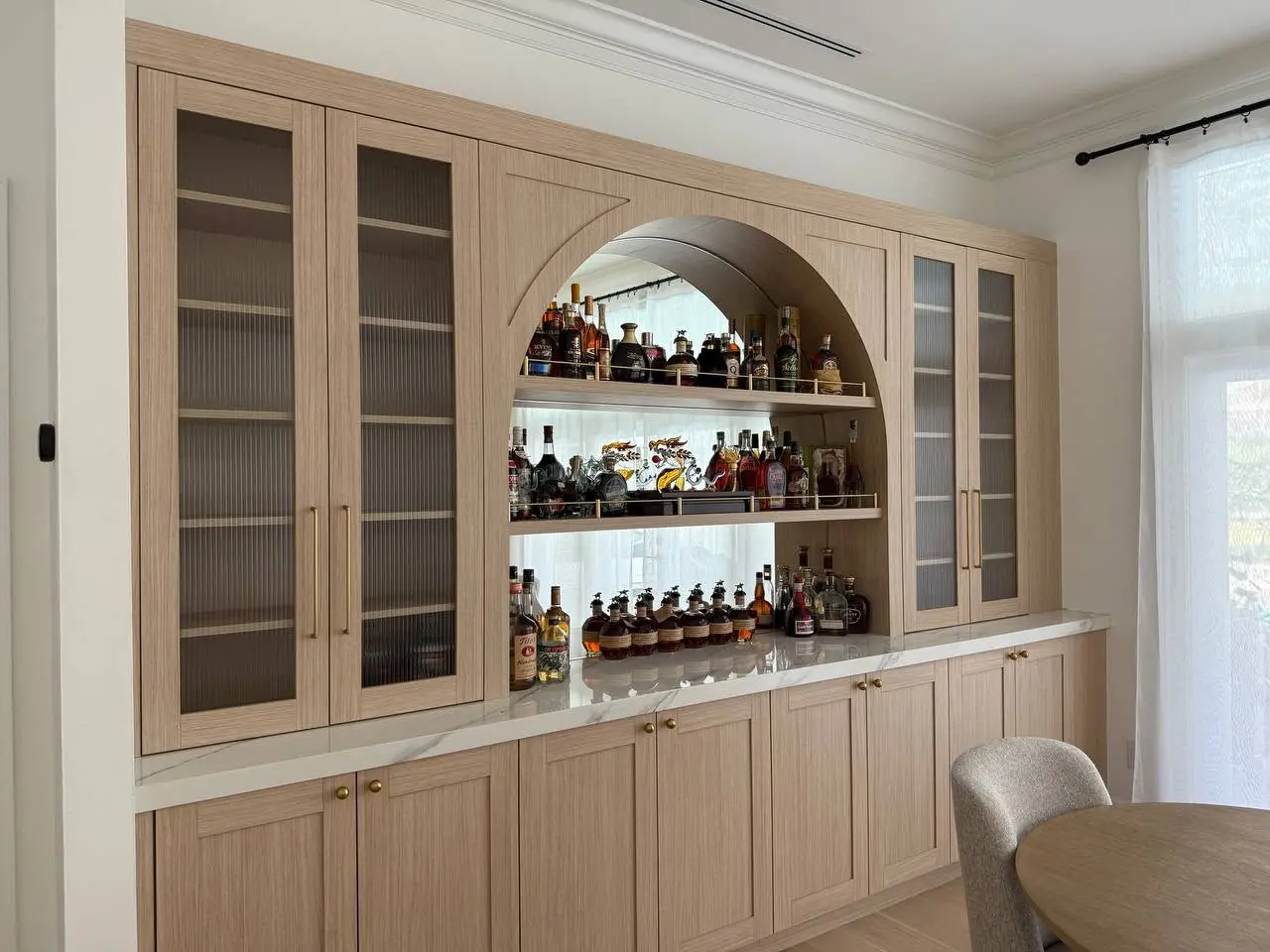 Angled view of the fluted-glass cabinetry and bar niche
