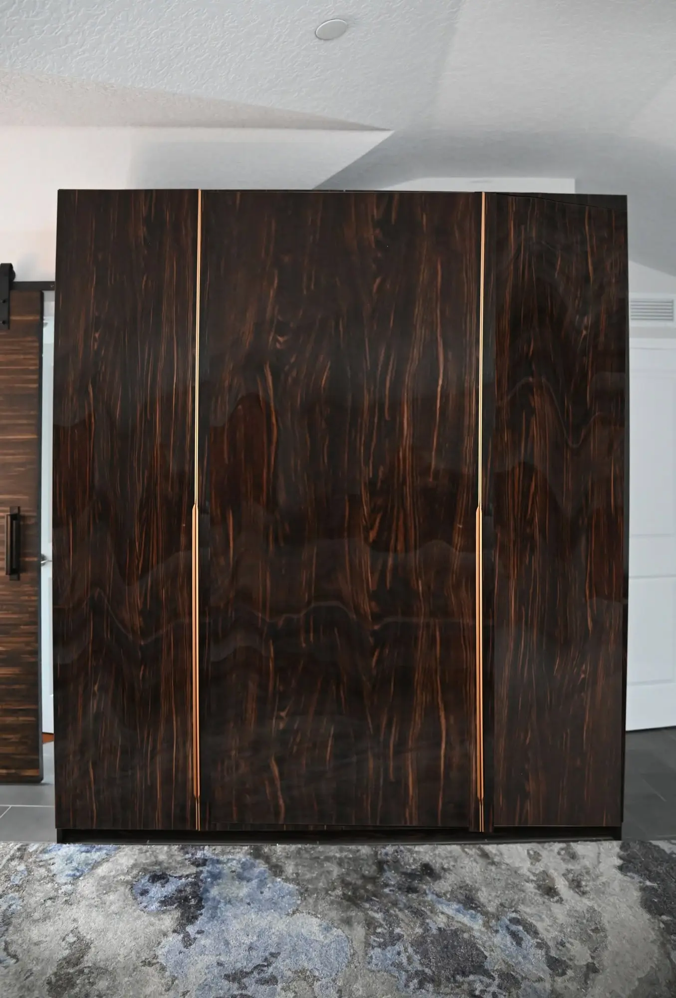 Completed high-gloss dark wood wardrobe with slim brass-toned pulls by LeVika Furniture